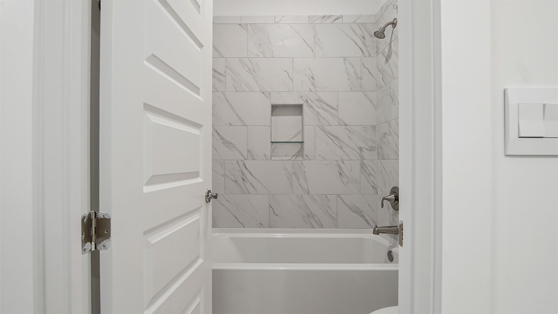 Bathroom two with shower room with toilet and shower tub with marbled tile walls.