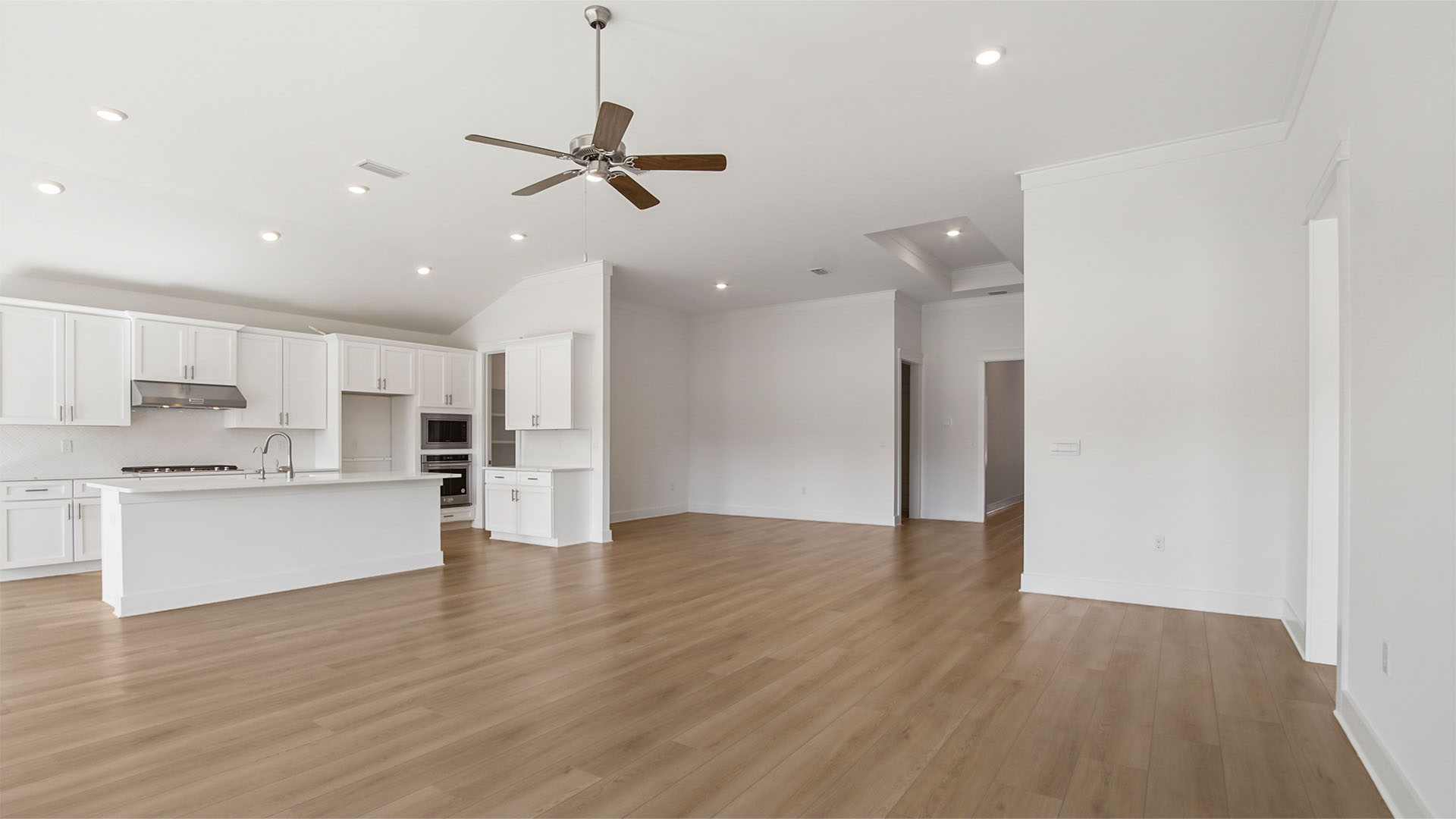 Living area with tall ceilings and ceiling fan and open kitchen next to dining area.