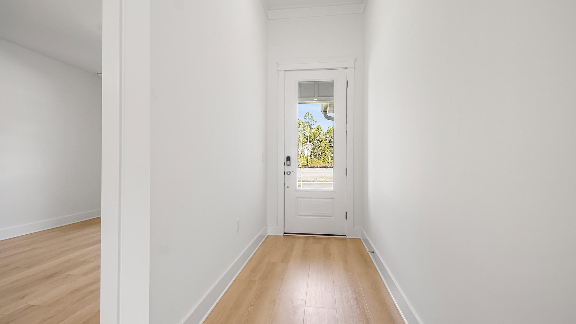 Foyer with glass front door and EVP flooring and hallway to guest bedroom and bathroom.