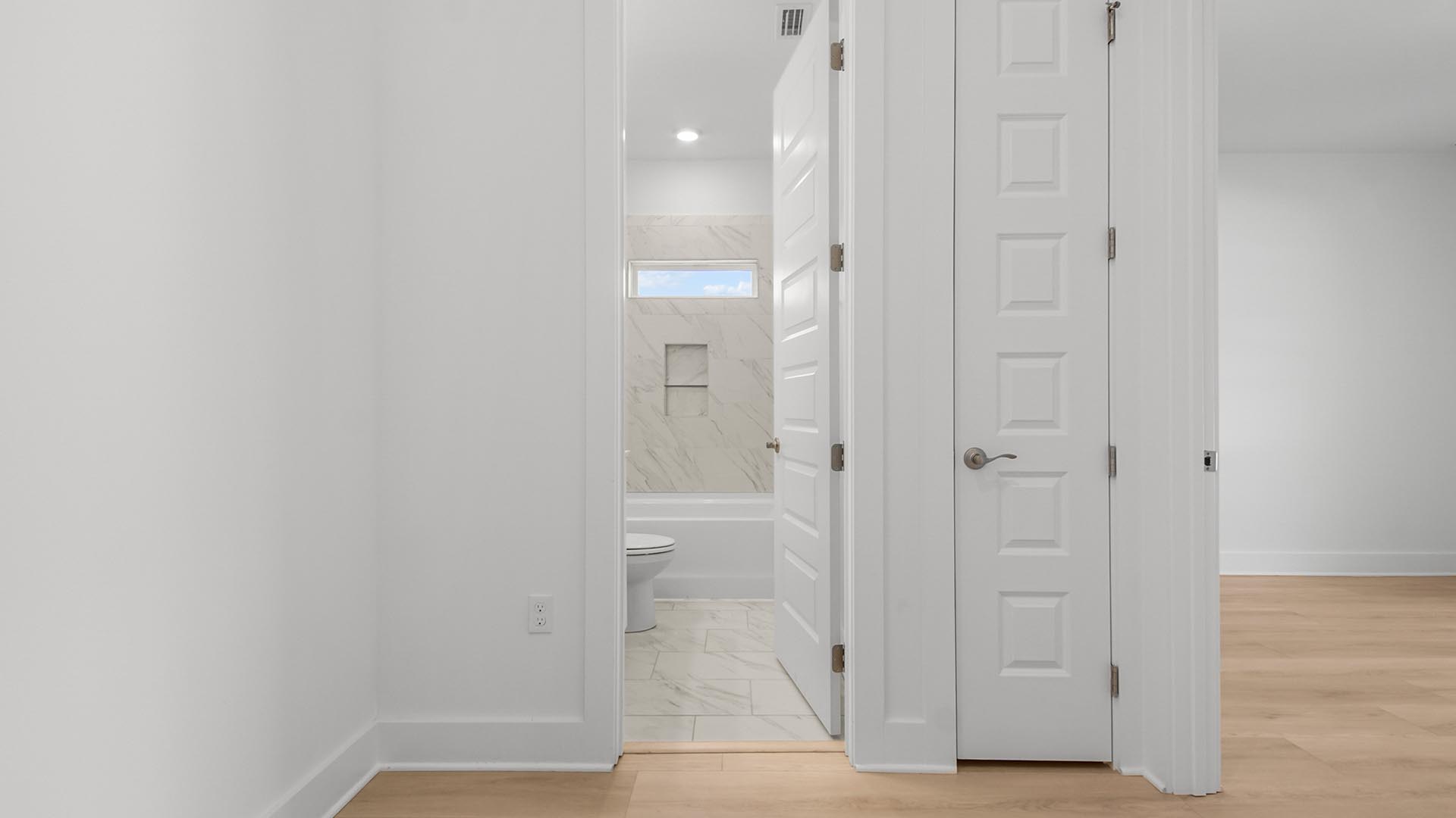 Hallway to guest bedroom and guest bathroom with EVP flooring and linen closet.