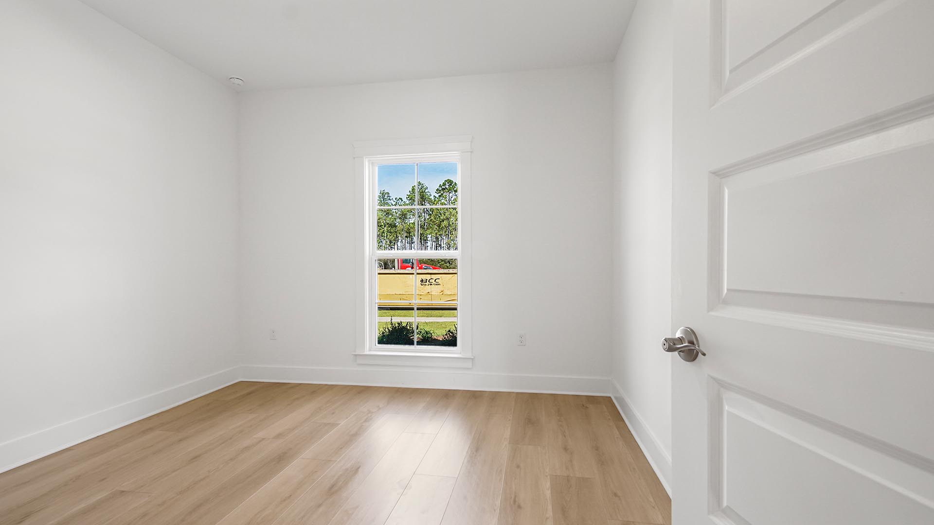Bedroom two with EVP flooring and large window and tall ceilings.