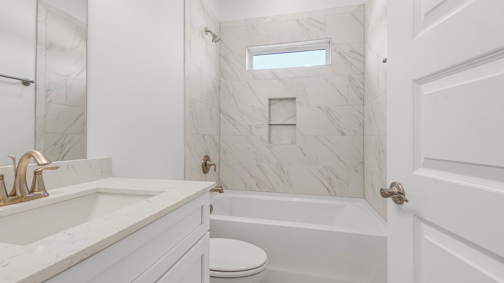 Full bathroom two with tub shower with marble tile backsplash and single vanity with quartz countertops and white cabinetry.