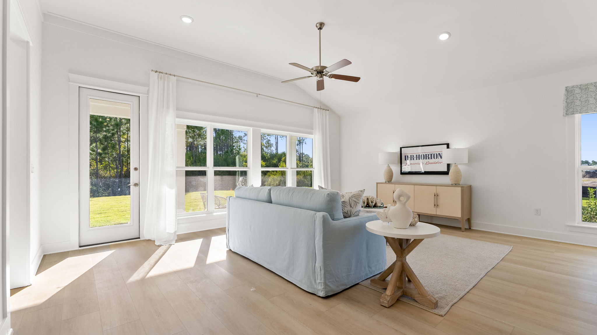 The living room is bright and airy with high ceilings and an installed ceiling fan