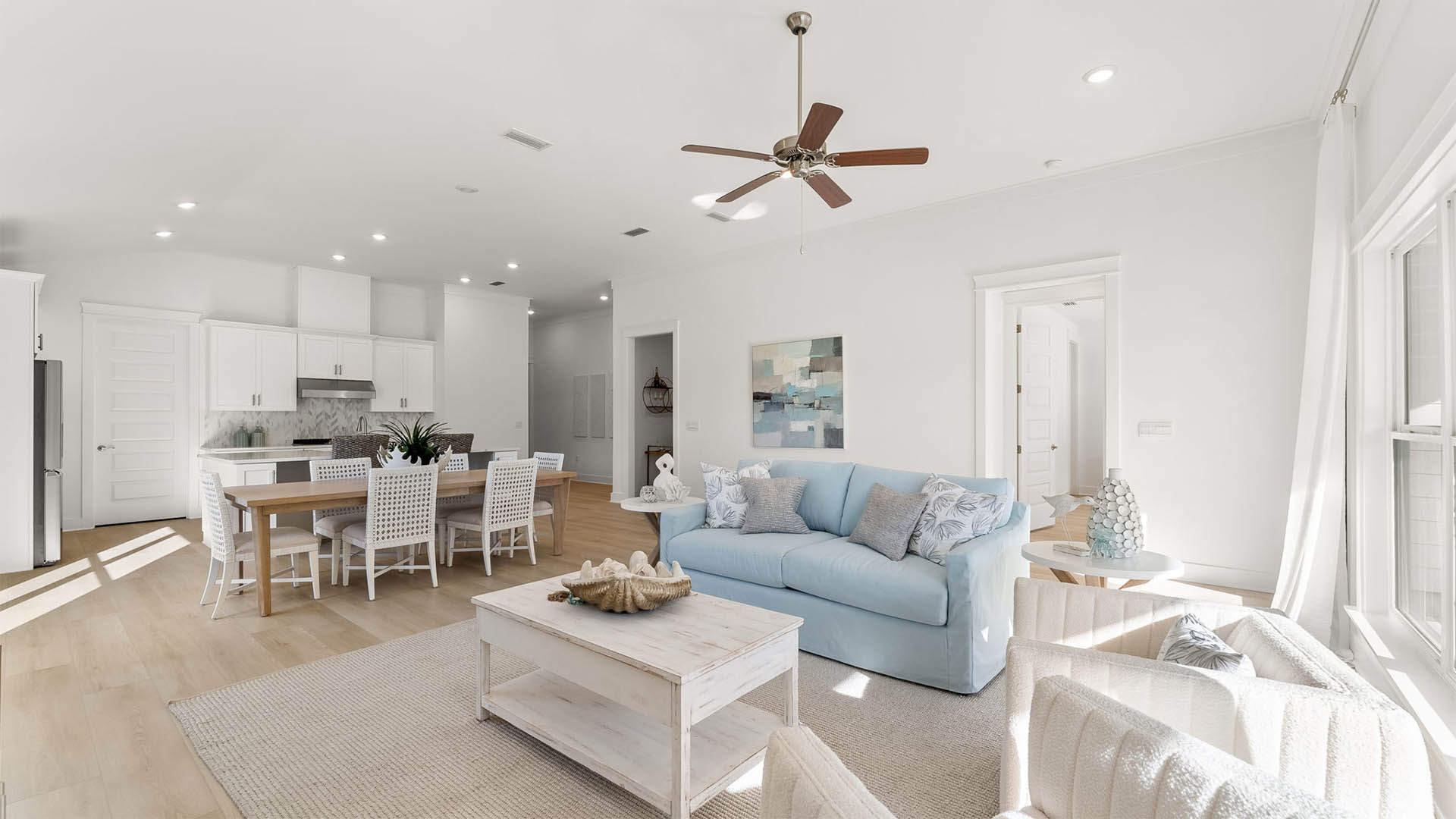 The living room is bright and airy with high ceilings and an installed ceiling fan
