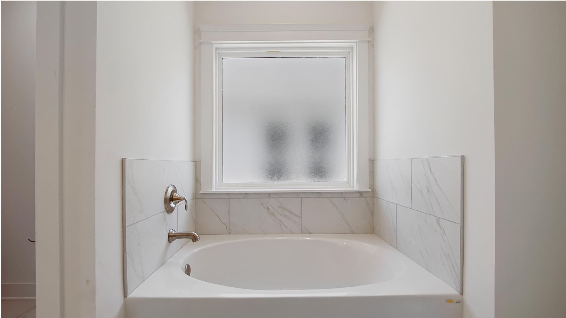 The large soak tub is illuminated by a large picture window with privacy glass