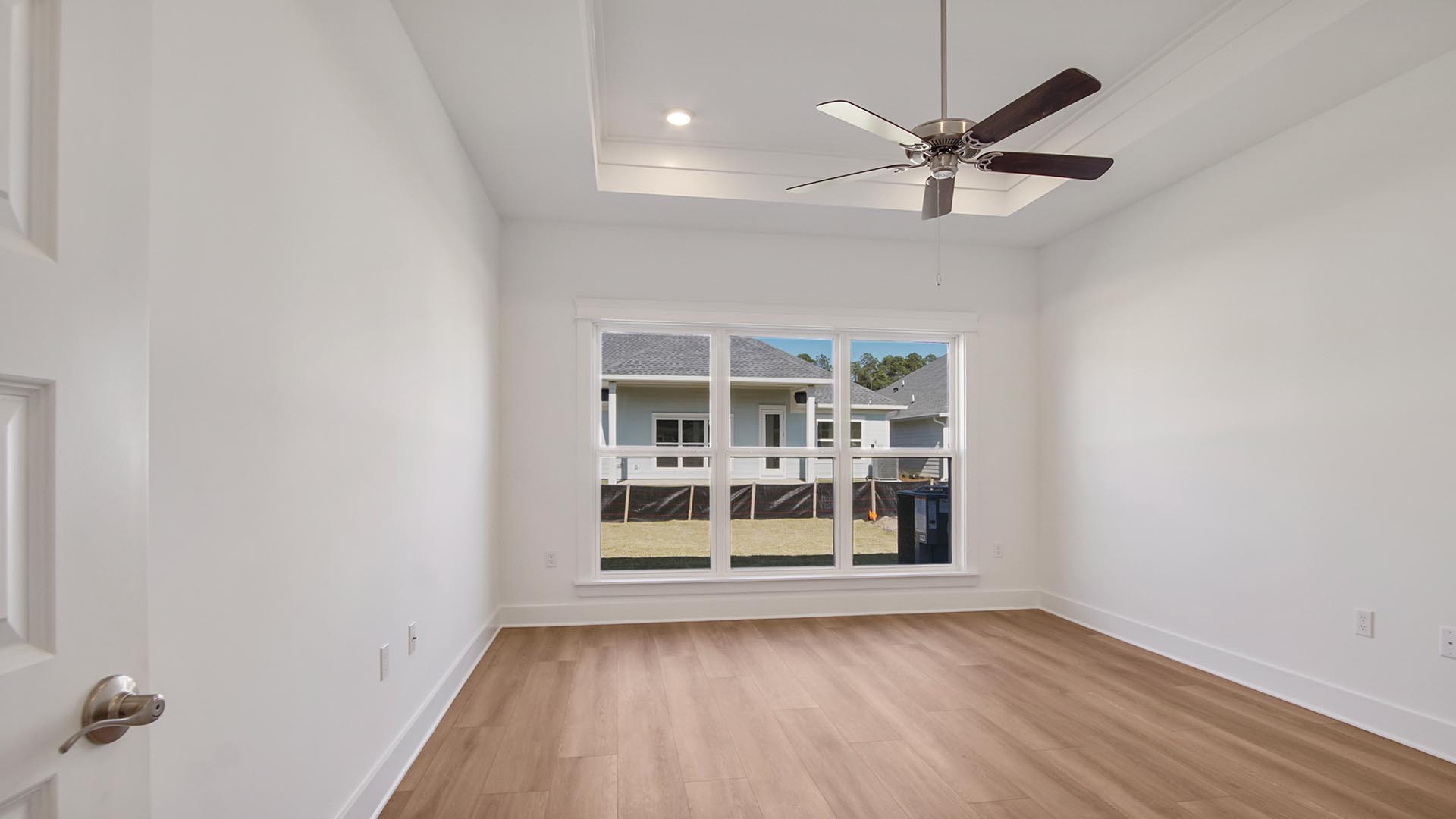 The spacious primary bedroom has wood floors and a ceiling fan