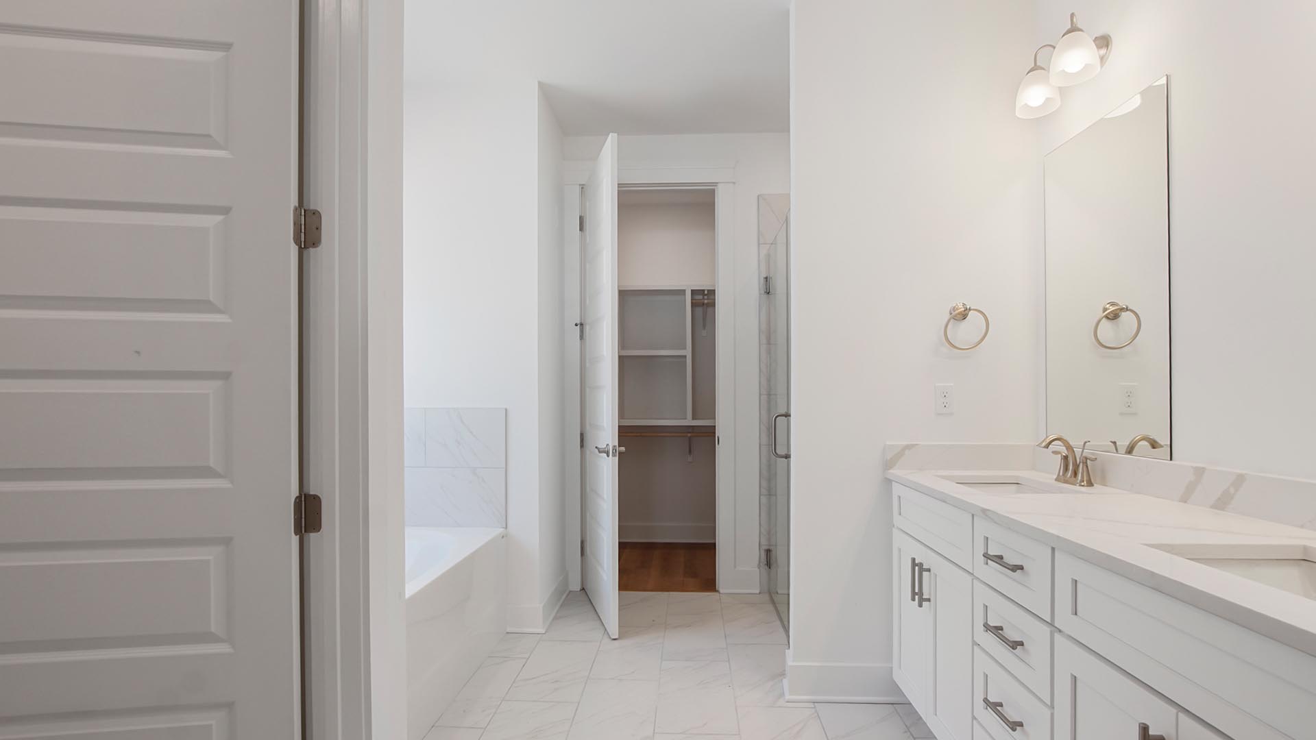 The primary bathroom has an elegant vanity with lower cabinetry, quartz countertops and dual sinks