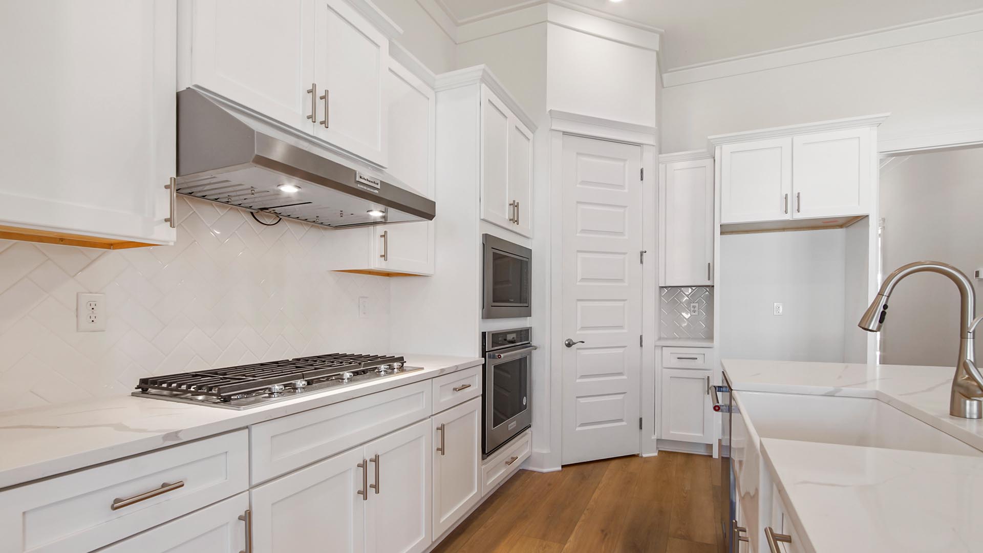 The kitchen features a gas cooktop stove with hood vent, bult in wall oven and microwave and a spacious corner pantry