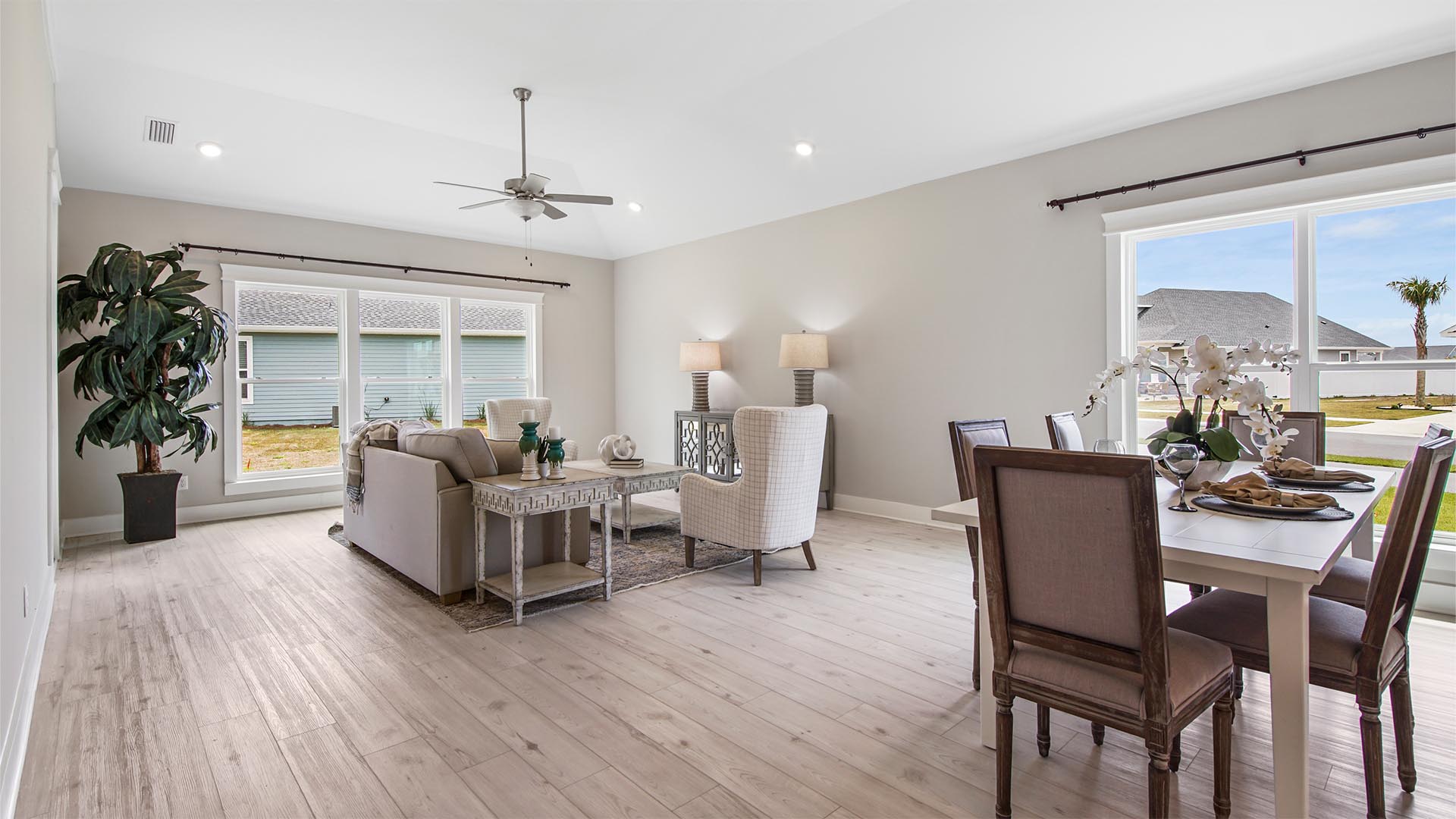 Open living area with dining area and large windows and EVP flooring and vaulted ceilings and ceiling fan.