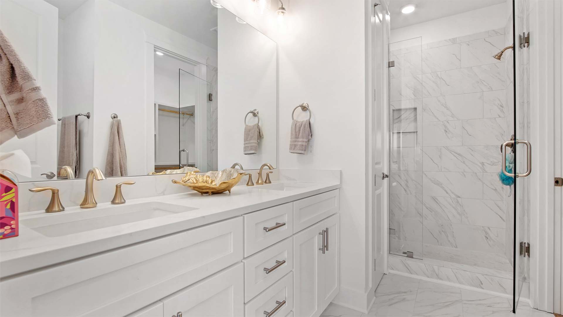 Primary bathroom with dual vanity with and oversized tile shower with glass door and linen closet.