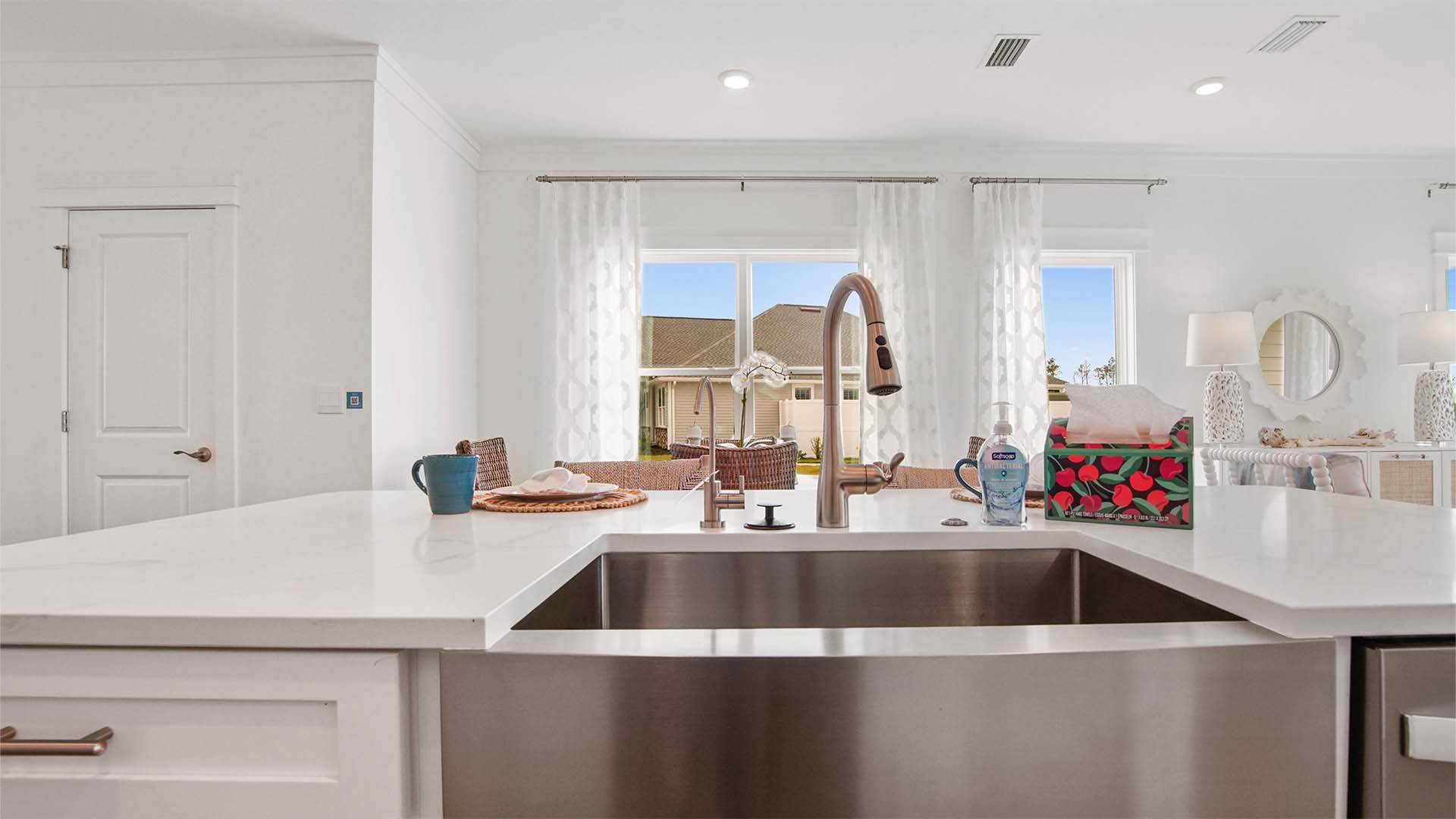 Kitchen island with quartz countertops and stainless-steel single basin undermount sink and dishwasher.