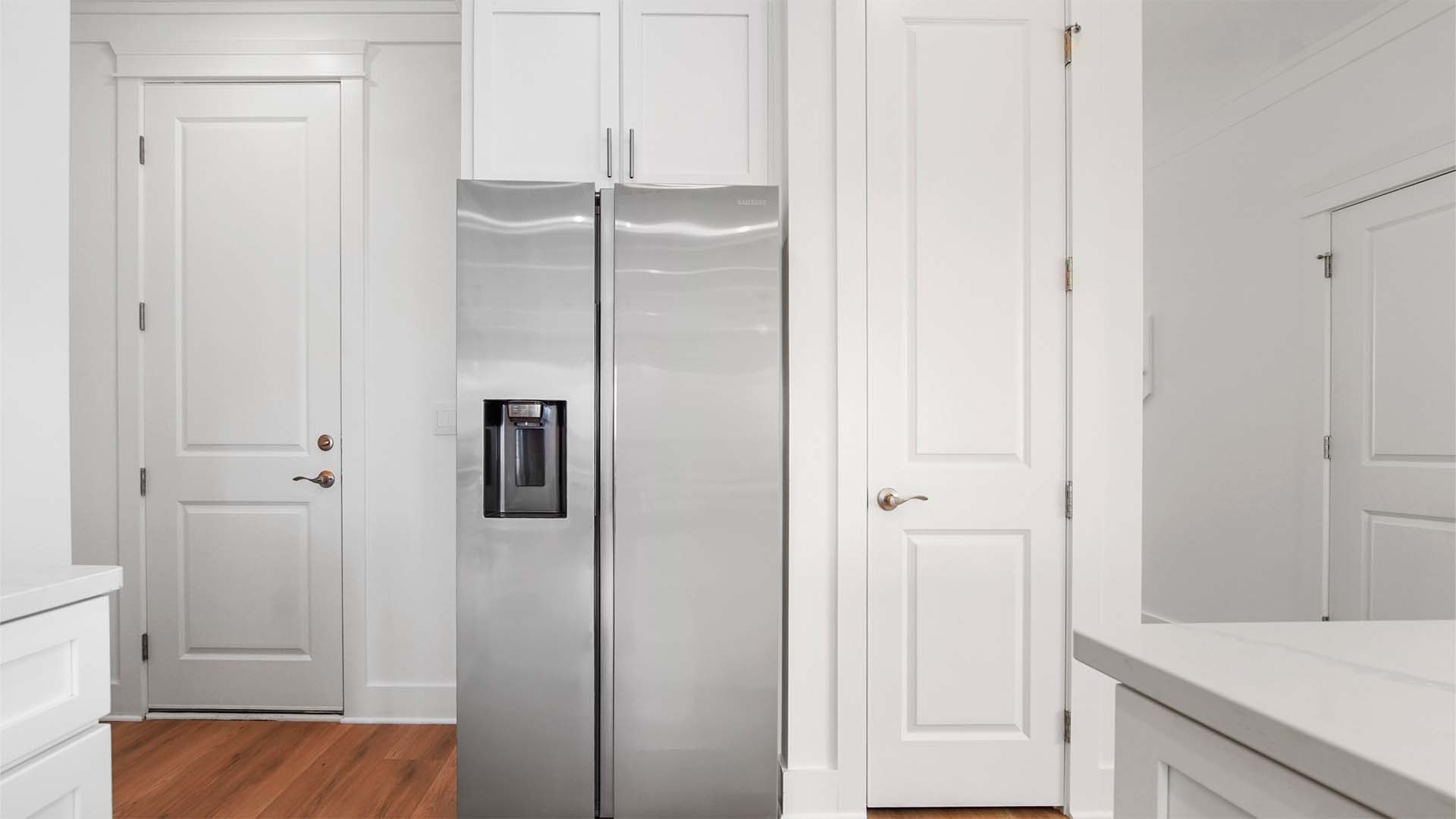 Kitchen with EVP flooring and pantry and white cabinetry and door to garage.