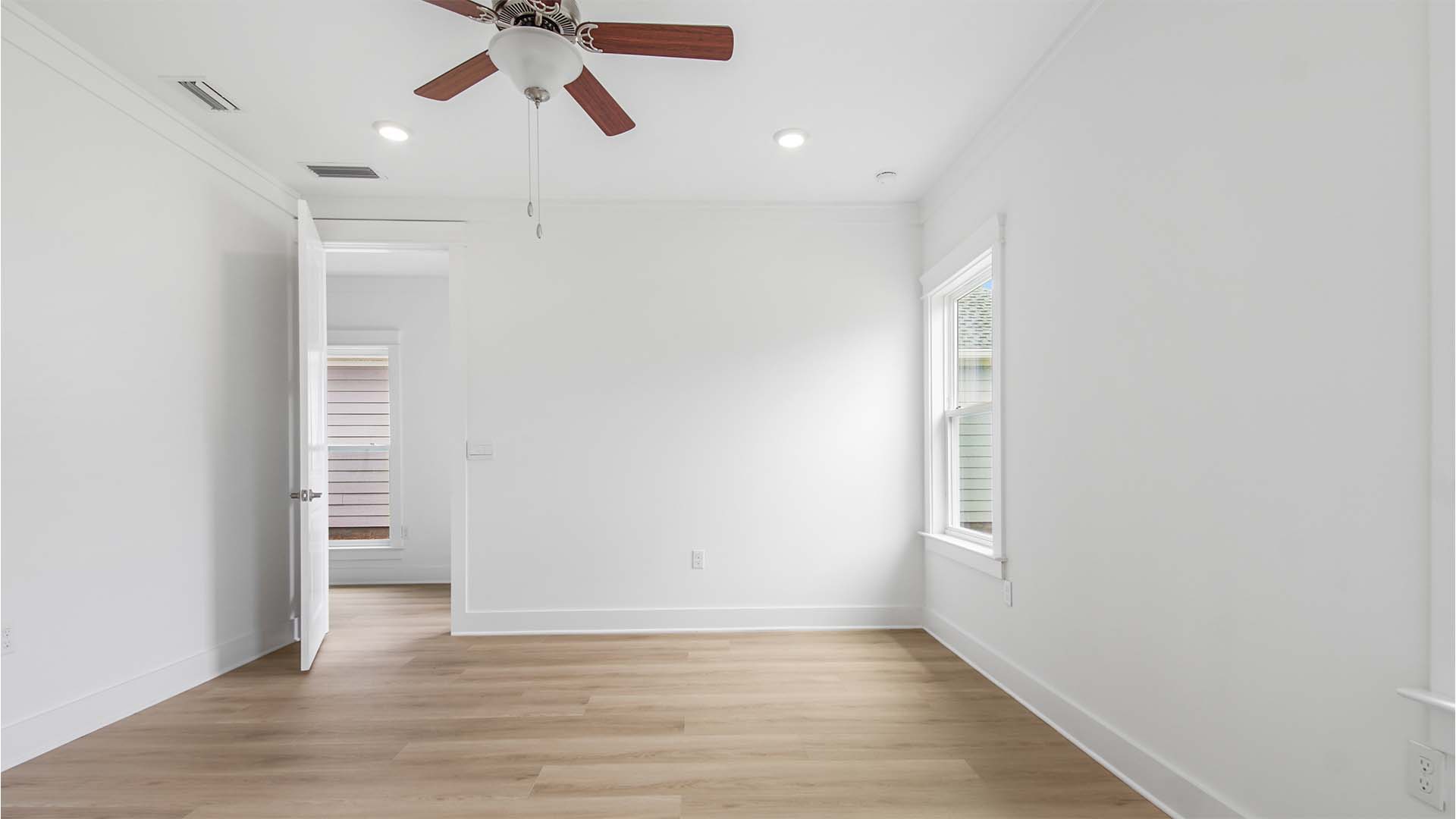 Primary bedroom with EVP flooring and large windows and ceiling fan.
