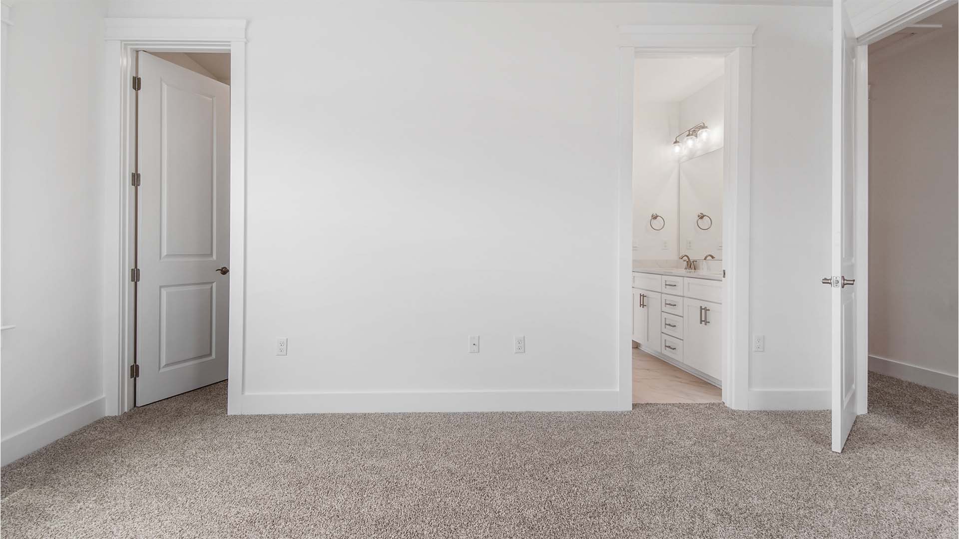 Bedroom two with carpet flooring and walk-in closet with wood shelving and jack and jill bathroom entrance.