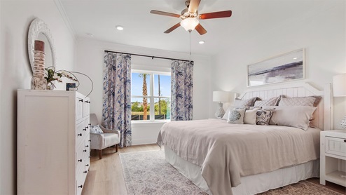 Breakfast Point Islamorada plan primary bedroom with large window and EVP flooring and ceiling fan.