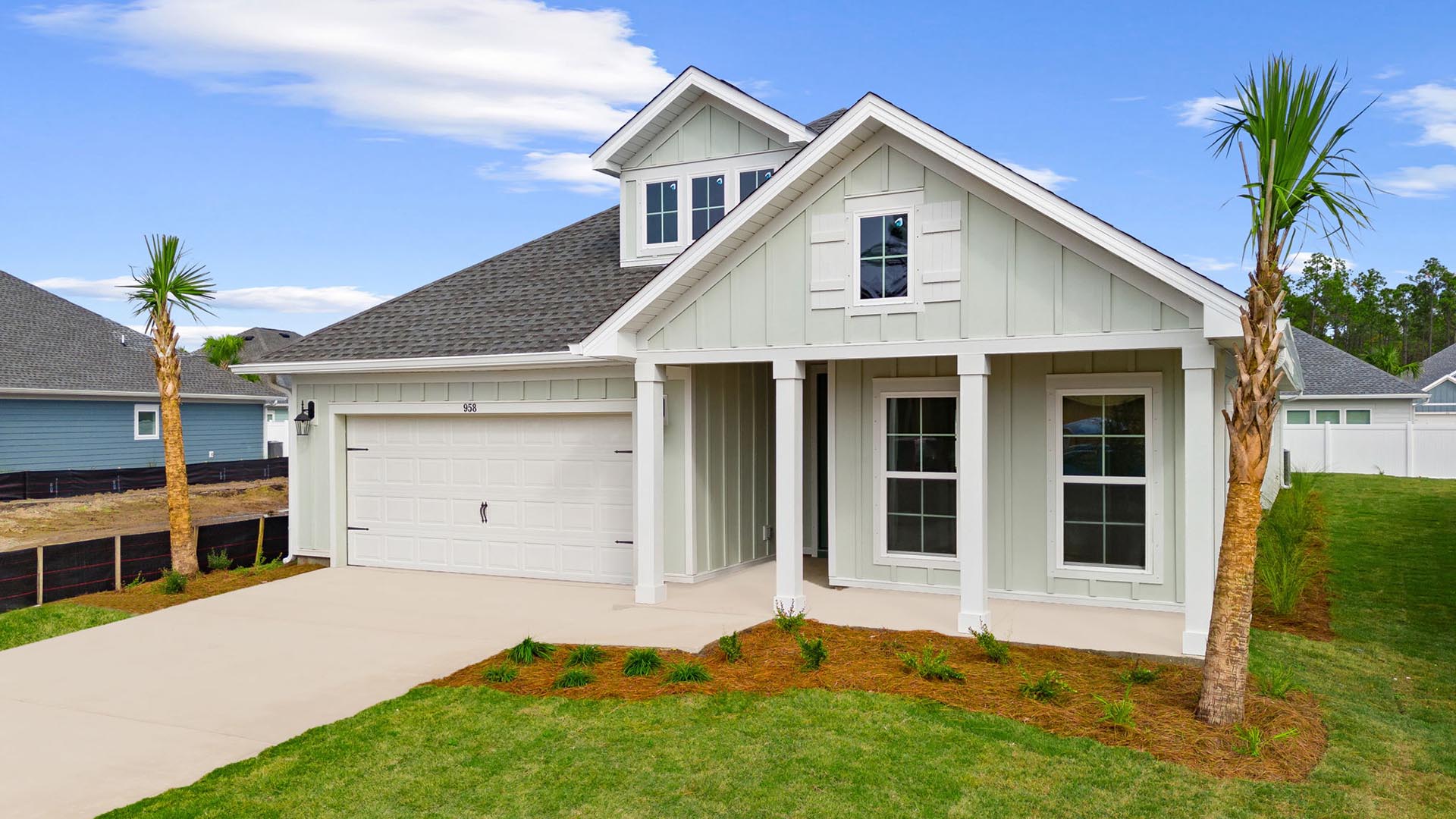 The exterior of this home is a light coastal green with white columns and Hardie exterior