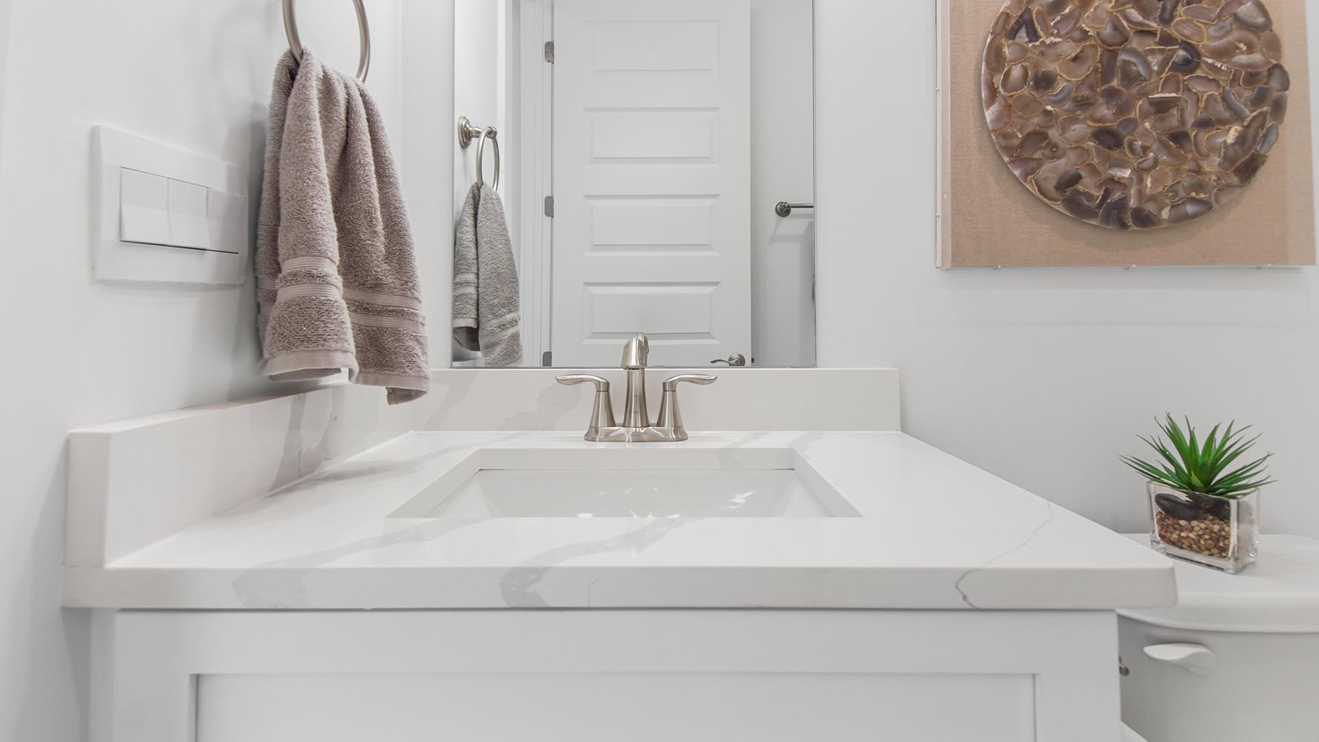 The shared bathroom has a single vanity with beautiful lower cabinetry and elegant quarts countertops