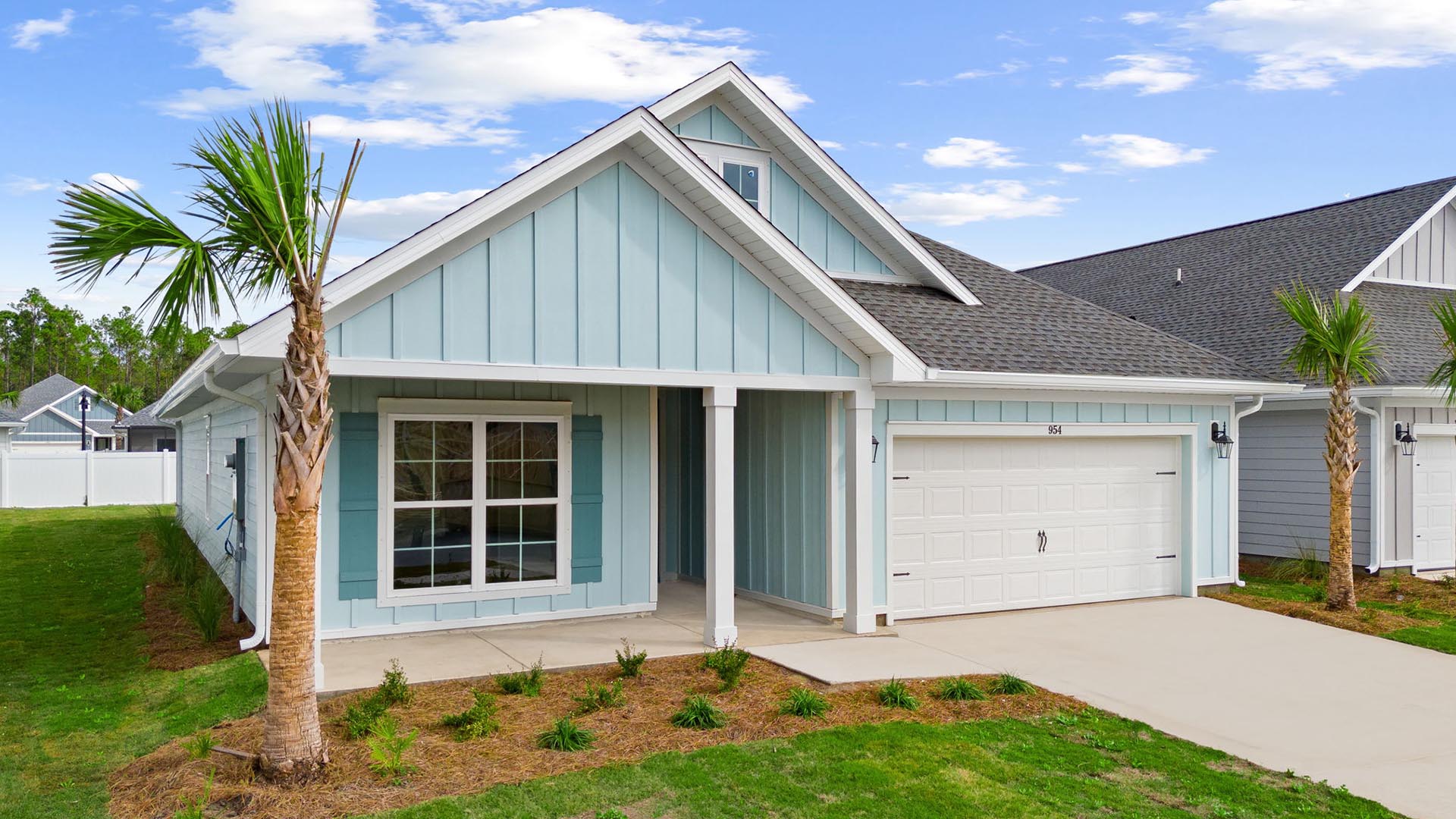 This home has a covered front porch the exterior is a coastal blue Hardie siding with white columns and a two car garage