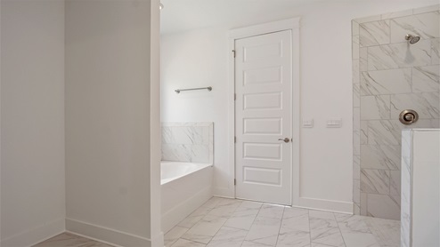 Primary bathroom with large soaking tub and marbled tile flooring and zero entry shower.