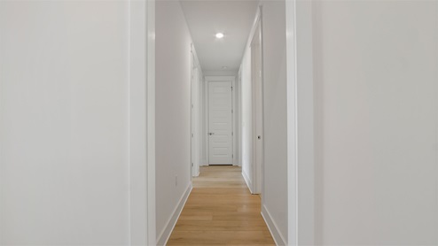 Hallway off foyer to guest bedrooms with EVP flooring and tall ceilings.