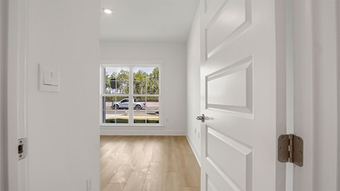 Bedroom two with large windows facing front of home with EVP flooring and tall ceilings.