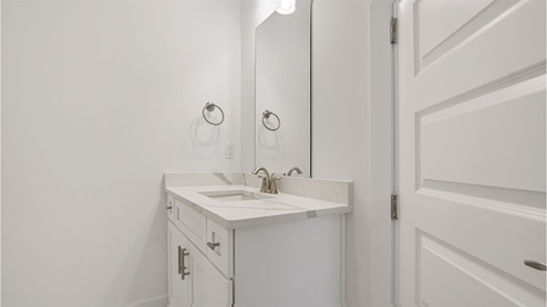 Bathroom two with second single vanity with quartz countertops and white cabinetry.
