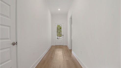 Foyer hallway with glass front door and storage closet and hallway to guest bedrooms.