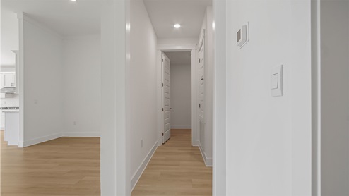 Hallway off foyer next to living area with EVP flooring and entrance to laundry room and garage door.