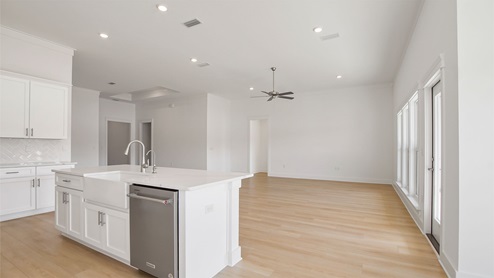 Open living area with EVP flooring and large windows and glass back door to covered back patio.