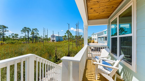 Covered back patio with white rail and wooden floor and wooden roof and patio furniture.