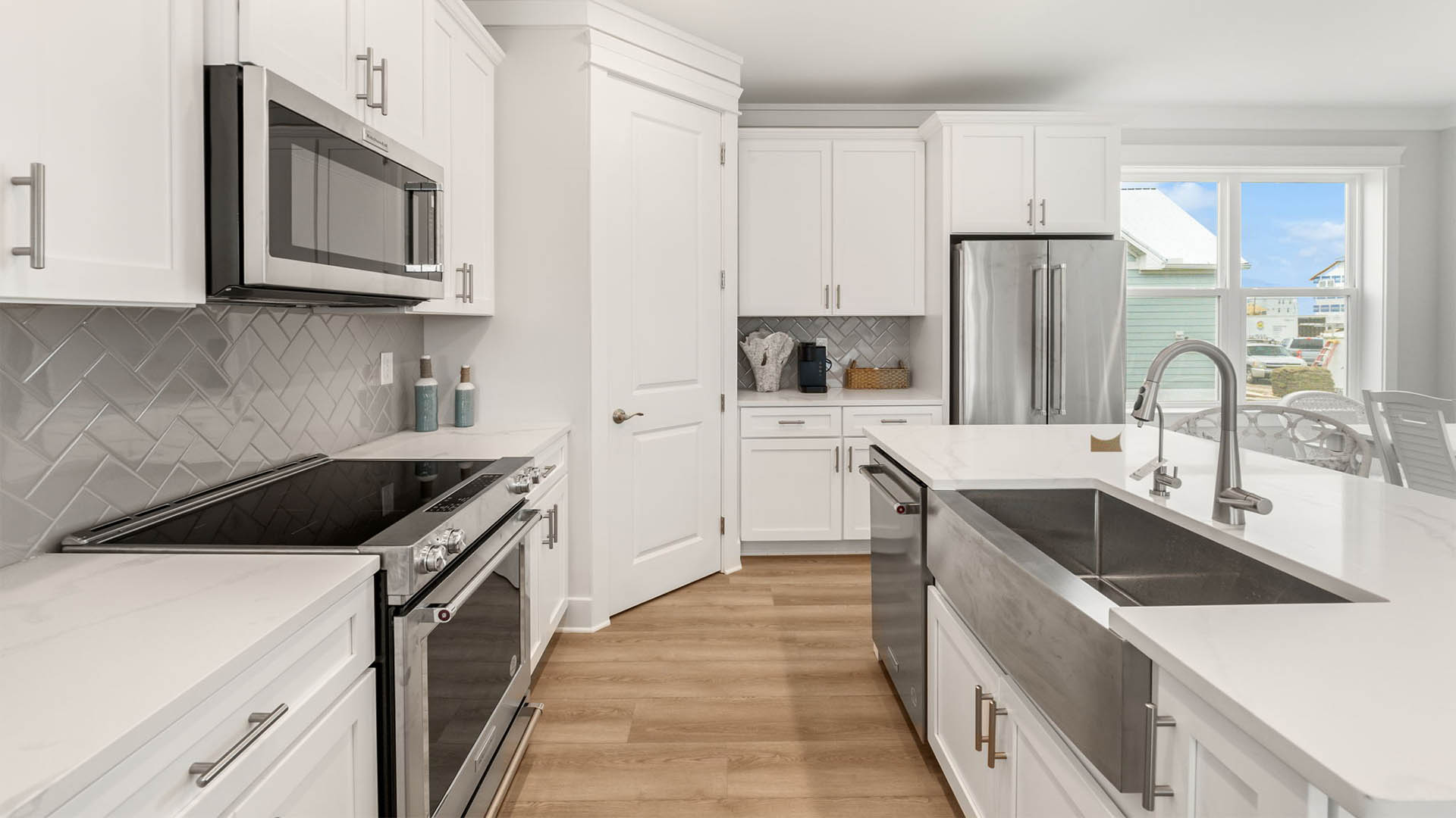 Kitchen island with quartz countertops and white cabinets and stainless-steel appliances.