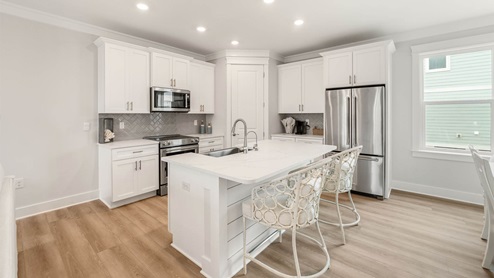 Kitchen island with quartz countertops and white cabinets and stainless-steel appliances.