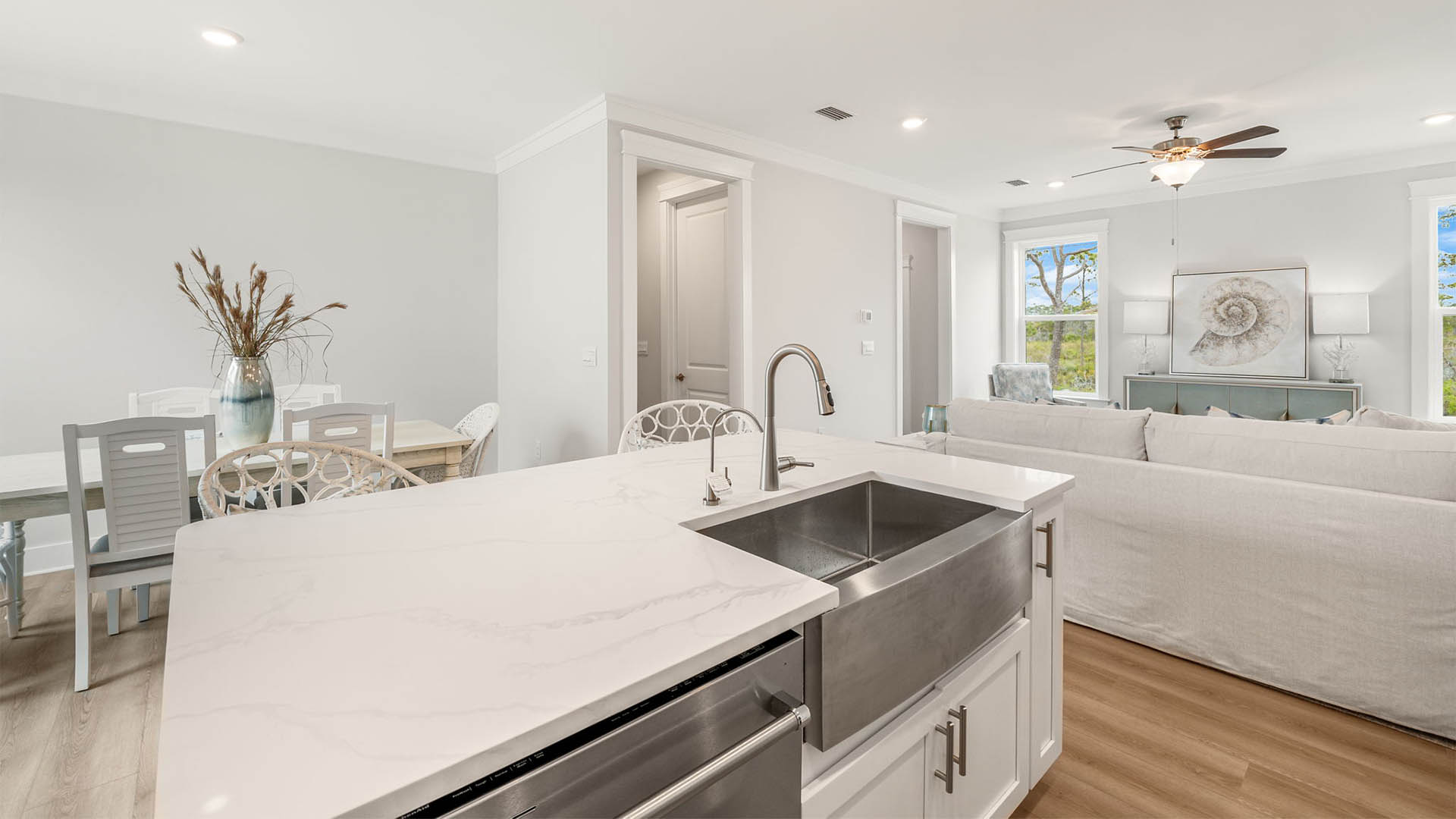 Kitchen island with quartz countertops and white cabinets and dining room table.