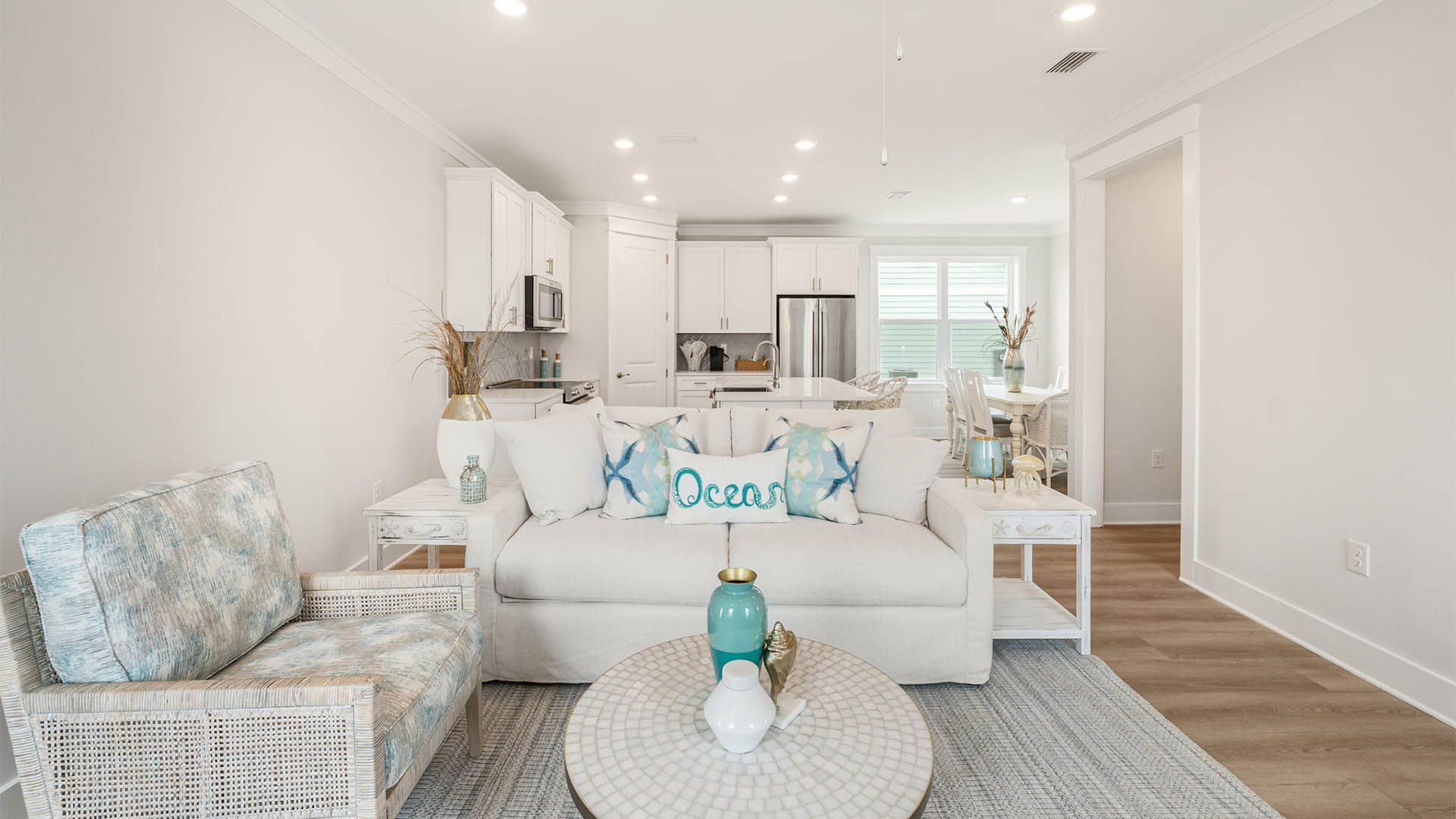Furnished living room with EVP flooring and kitchen with white cabinets.