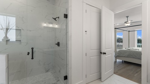 Luxury bathroom with walk-in shower by bedroom door.