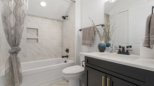 Bathroom with single vanity white quartz countertops and shower and tub.