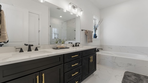 Bathroom with double vanity quartz countertops and tub.
