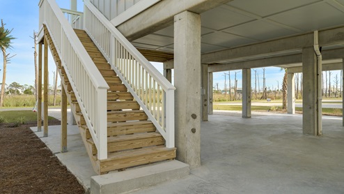 Carport under pilings with wooden steps.