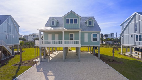 Two story home on pilings with covered front porch.