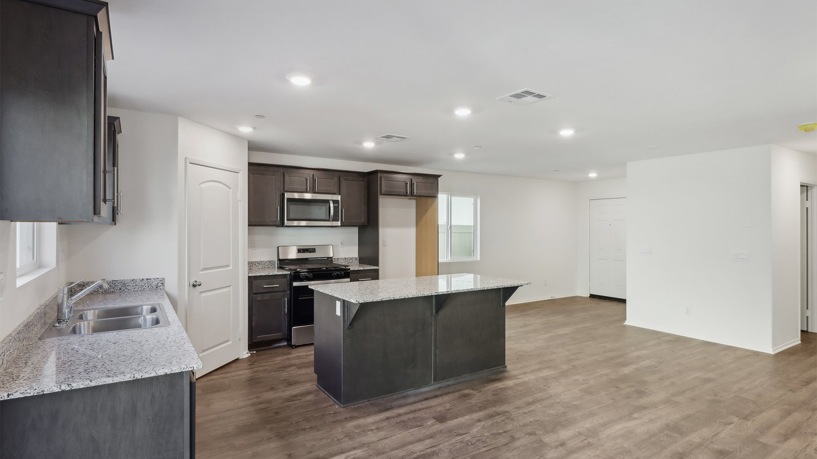Open kitchen with dark cabinets granite countertops and stainless steel appliances