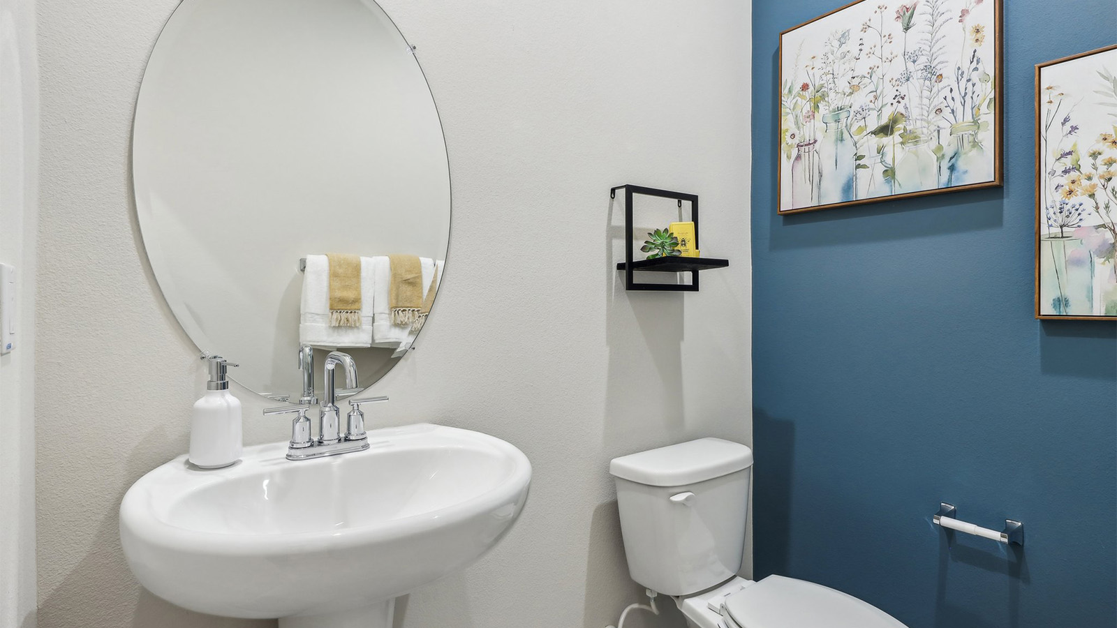 Powder bathroom with pedestal sink and oval mirror