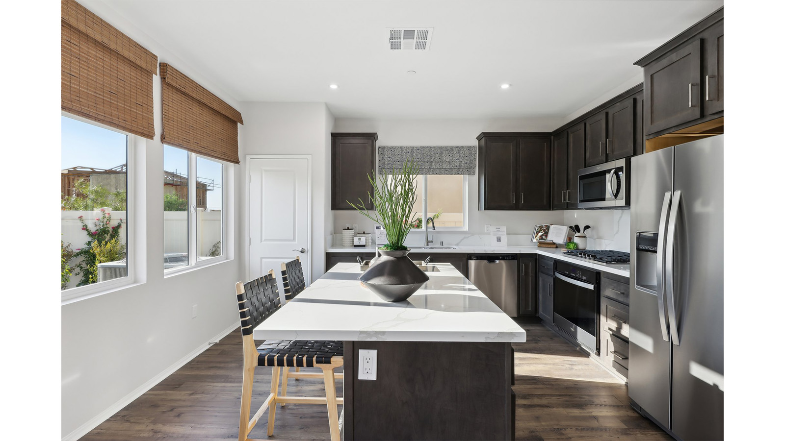 Open kitchen with dark cabinets quartz countertops and stainless steel appliances