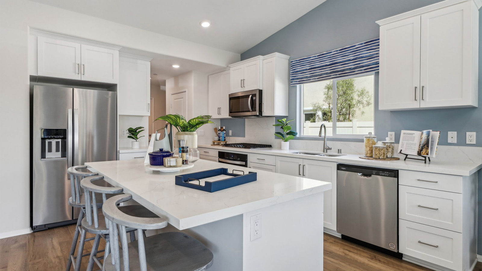 Modern kitchen with white cabinets quartz countertops and stainless steel appliances