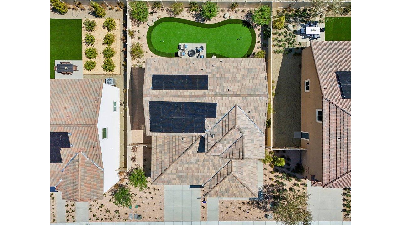 Aerial photo of two story house with solar panels and turf backyard