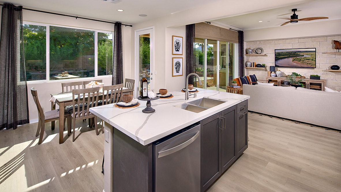 Open-concept kitchen area with dark cabinets quartz countertops and stainless steel appliances