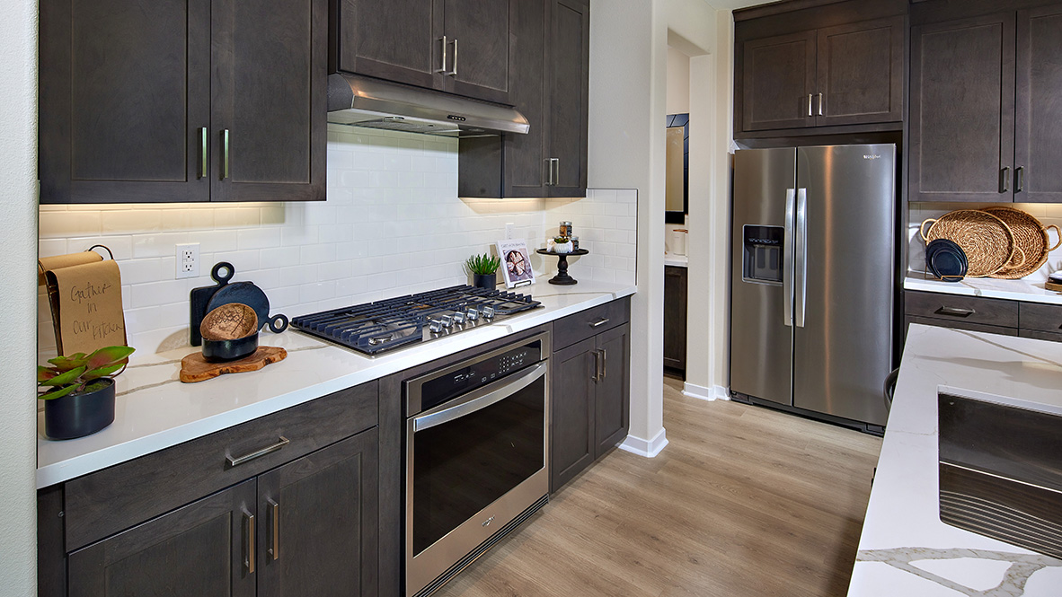 Open-concept kitchen with dark cabinets quartz countertops and stainless steel appliances