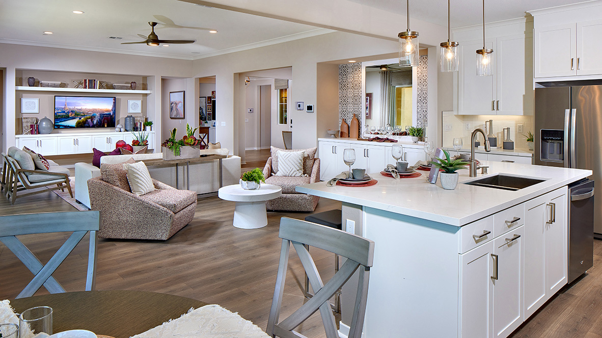 Open-concept kitchen area with white cabinets, quartz countertops and stainless steel appliances