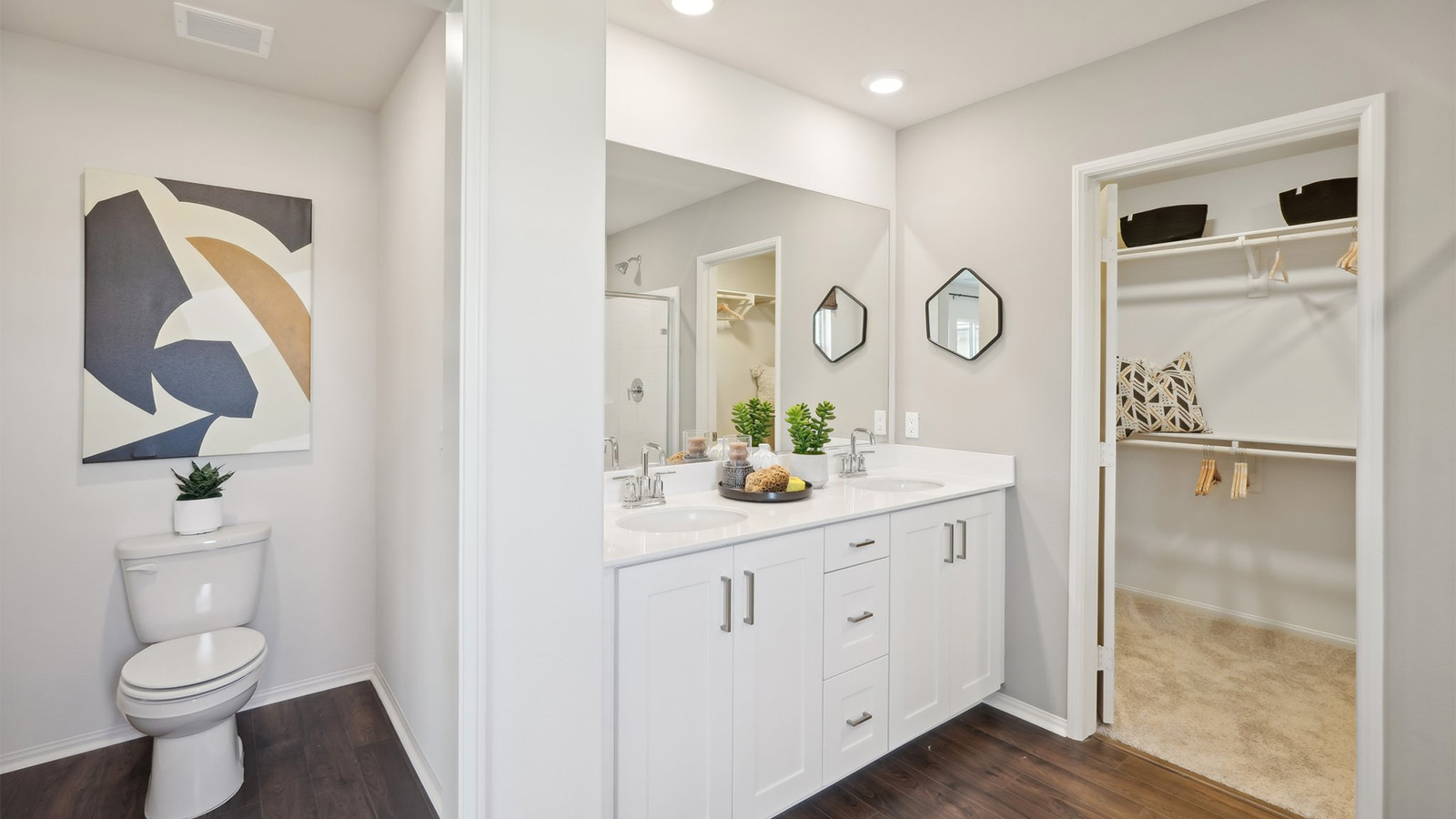 primary bathroom with dual vanities and shower