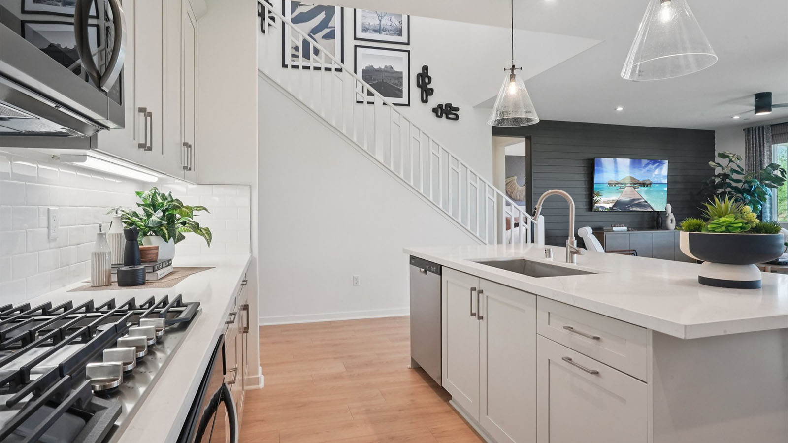 Modern kitchen with light grey cabinets quartz countertops and stainless steel appliances
