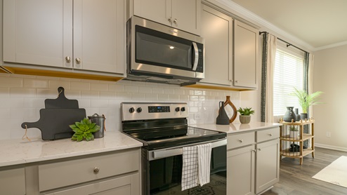 Grey cabinets with stainless steel appliances and quartz countertops